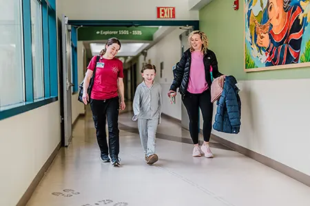 A young family walk down a corridor of a healthcare facility