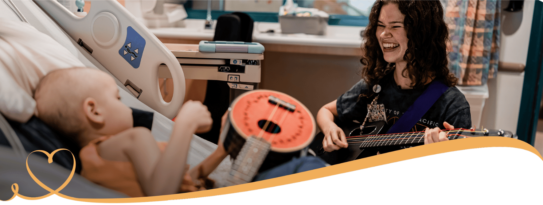 A Child Life specialist smiles as she plays music with a patient