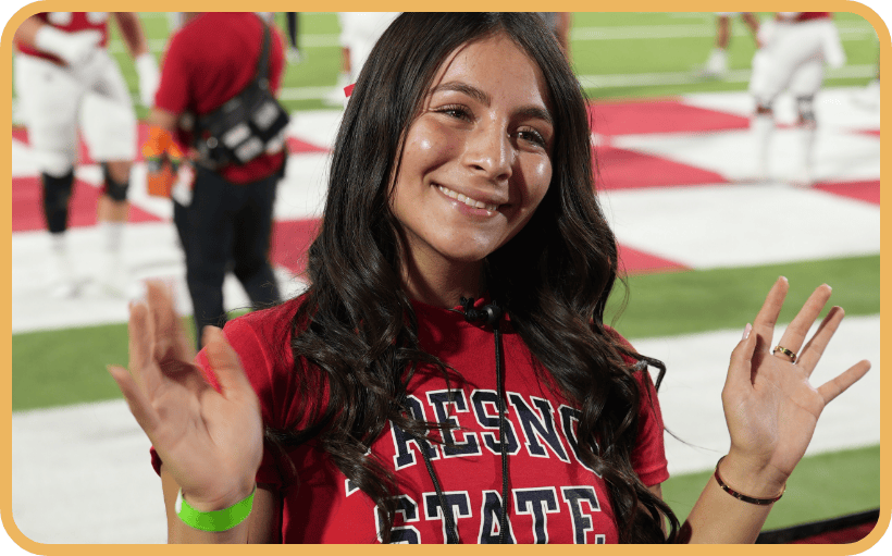 A teen girl smiles at a Fresno State football game