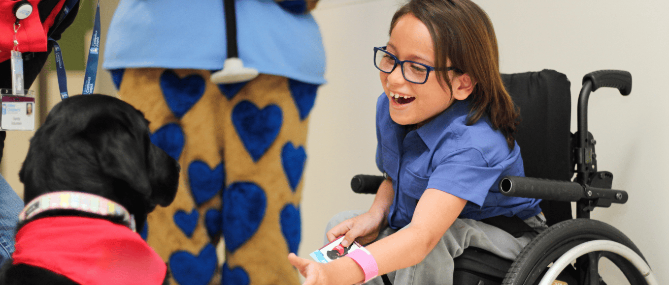Sylus smiles as he pets a therapy dog