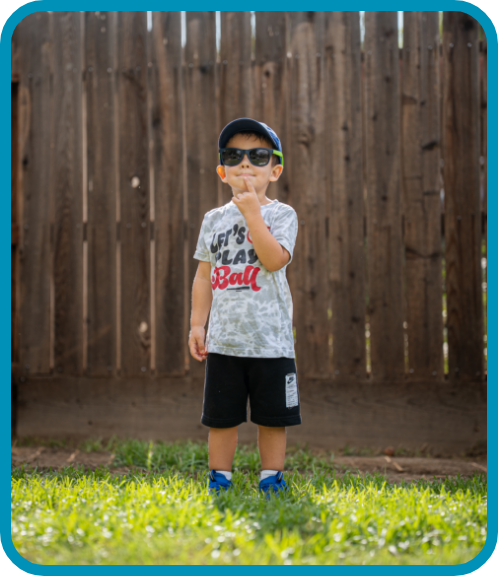 A young boy plays outside with sunglasses