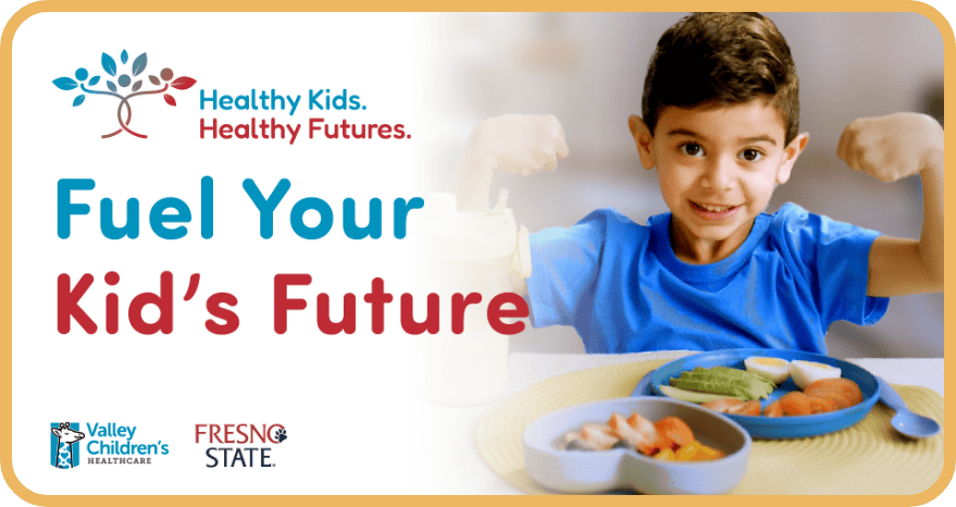 A young boy flexes his muscles as he eats vegetables